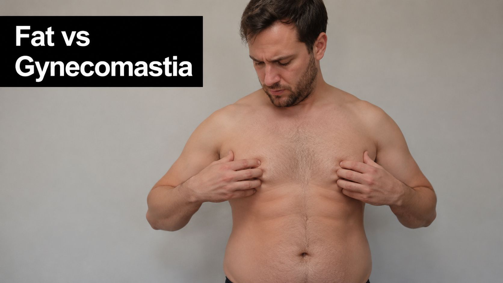 A shirtless man examining his chest area to distinguish between excess fat and gynaecomastia tissue.